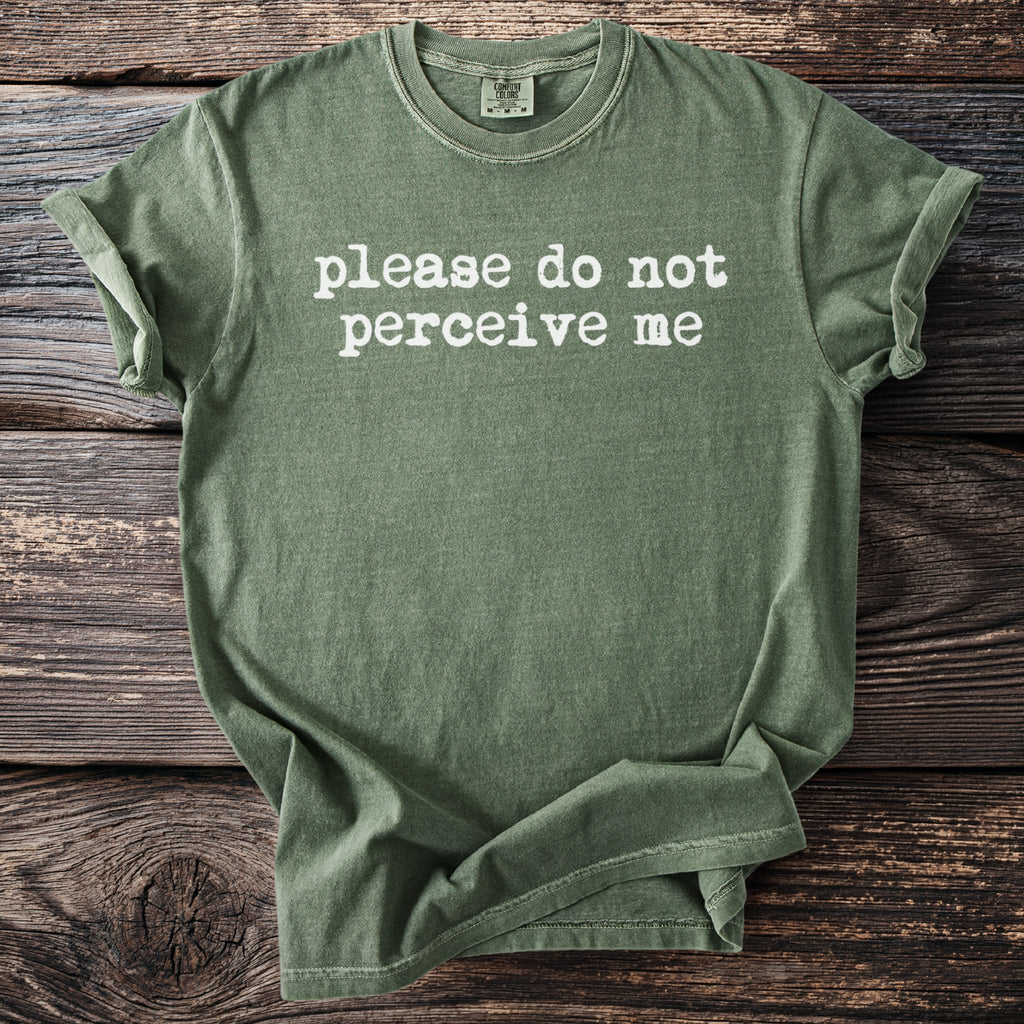 Green t-shirt with white text that reads "please do not perceive me".