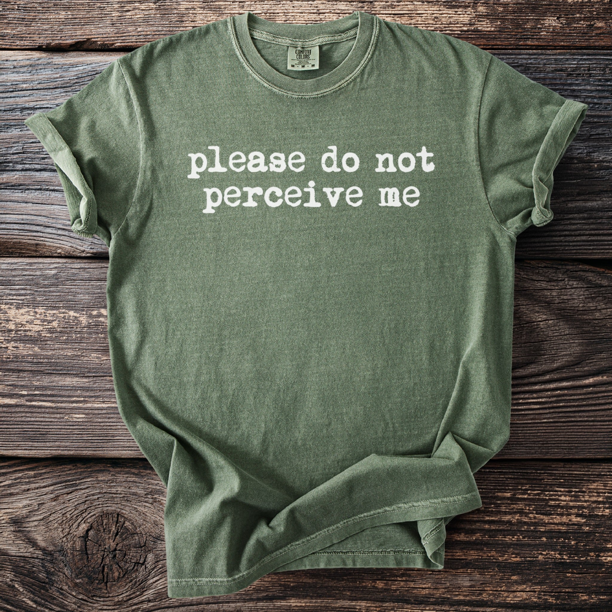 Green t-shirt with white text that reads "please do not perceive me".