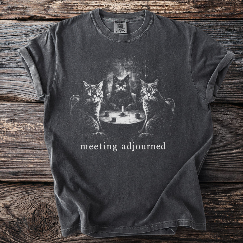 Dark t-shirt with three cats sitting around a table with a candle. "meeting adjourned" text.