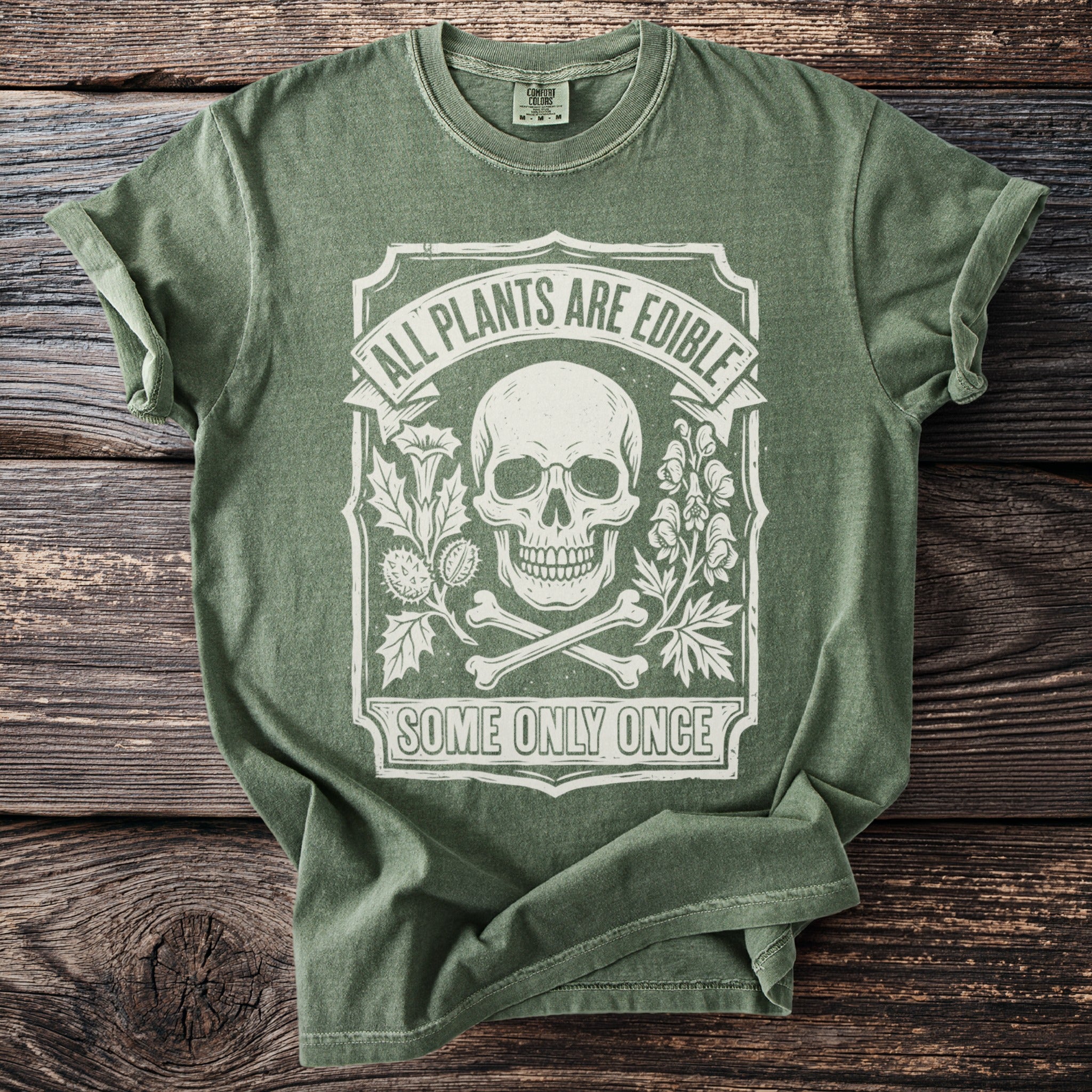 Green t-shirt with skull, bones, plants, and text "All Plants Are Edible Some Only Once".