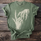 Green t-shirt with an off-white graphic of two spooky, clawed hands on a wooden background.