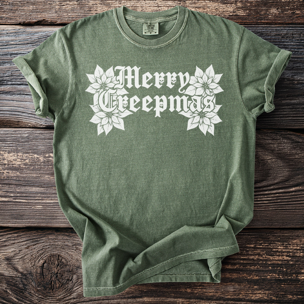 Green t-shirt with white "Merry Creepmas" text and poinsettias with skull details.