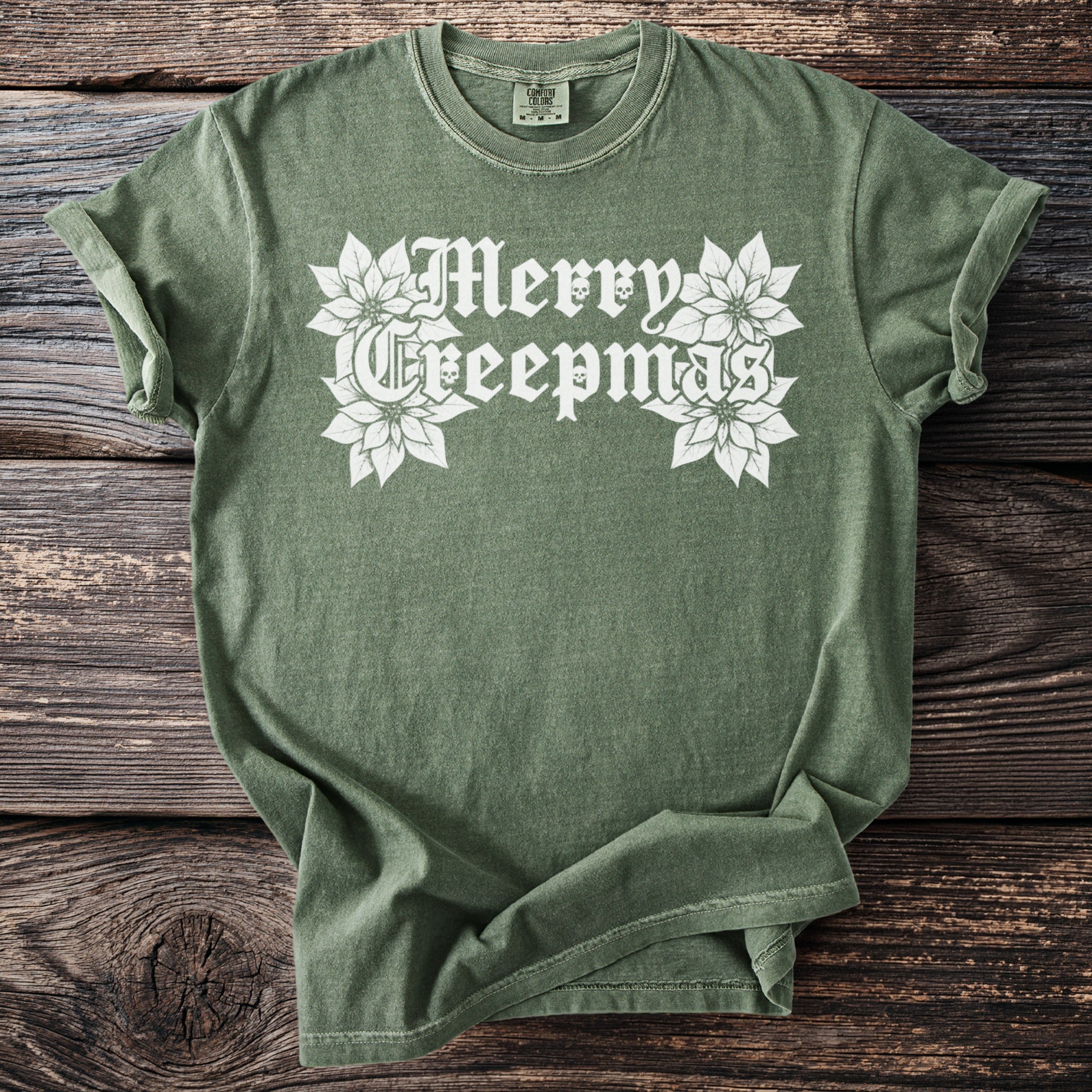 Green t-shirt with white "Merry Creepmas" text and poinsettias with skull details.