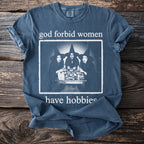 Blue t-shirt with graphic of three witches and text "god forbid women have hobbies".