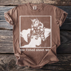 Brown t-shirt with a graphic of a werewolf on a bed and text "the fitted sheet wo".