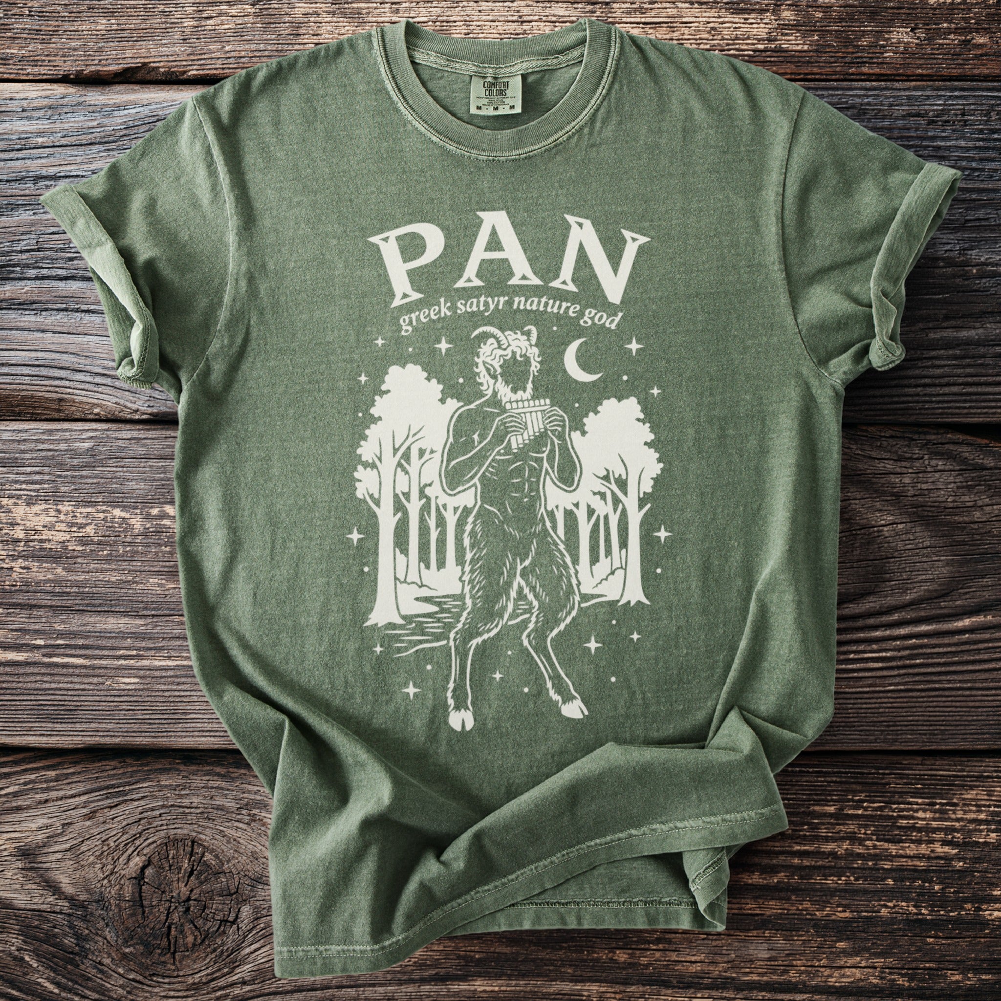 Green t-shirt with a white graphic of the god Pan playing panpipes in a forest.