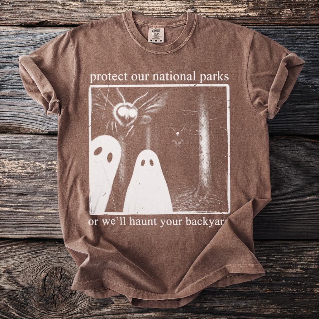 Brown t-shirt with graphic and text "protect our national parks or we'll haunt your backyard".