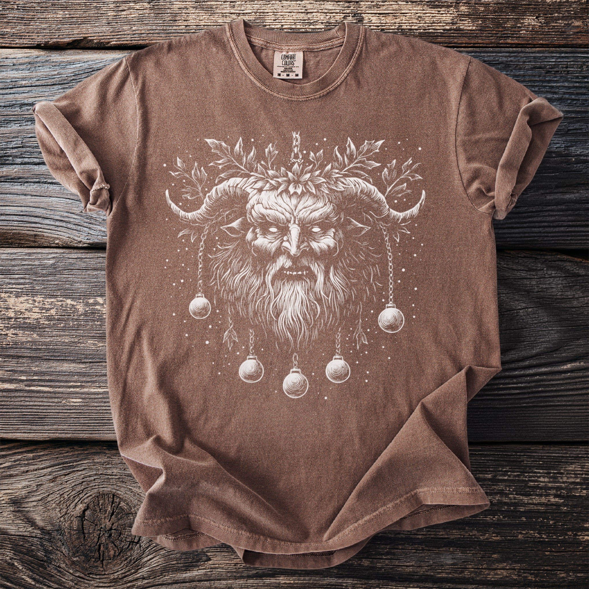 Brown t-shirt with a white print of a horned, bearded figure and ornaments.