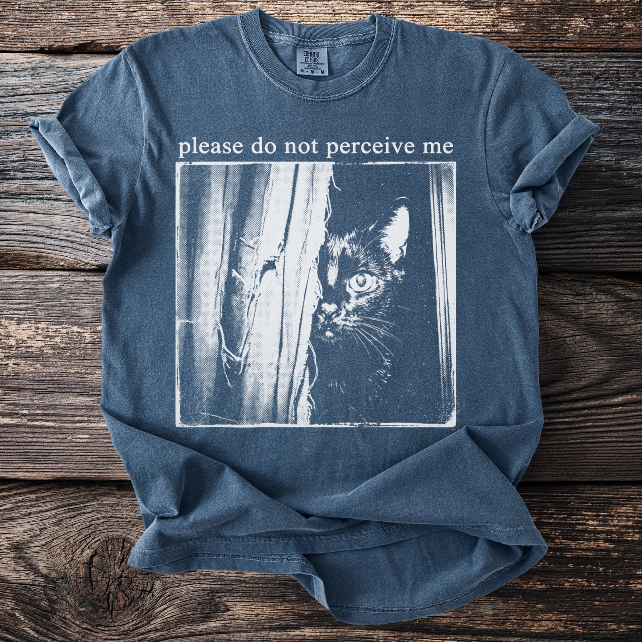 T-shirt with text "please do not perceive me" and a black cat peeking.