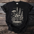 Black t-shirt with botanical illustration of medicinal herbs and text "The Herbalist's Garden".