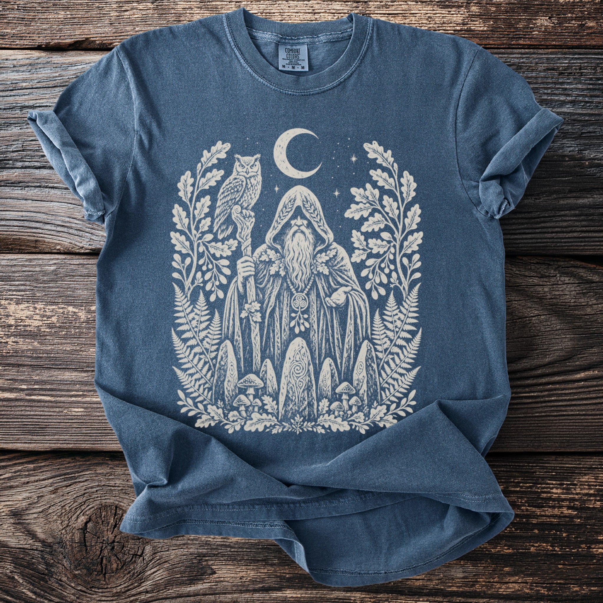 Blue t-shirt with a white ink drawing of a wizard, owl, moon, and forest elements.