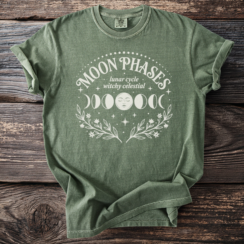 Green t-shirt with "Moon Phases lunar cycle witchy celestial" text and moon graphics.