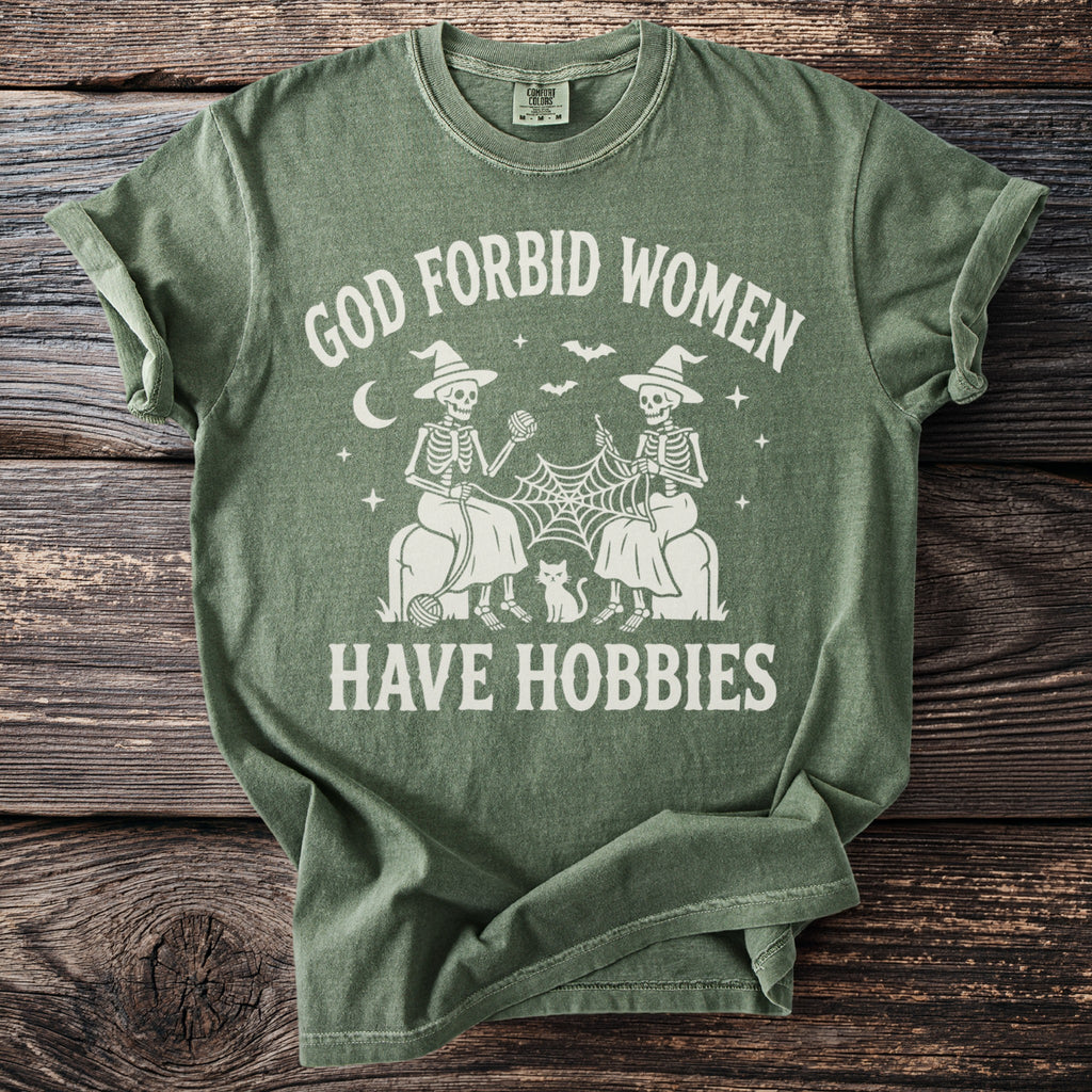 Green t-shirt with "God Forbid Women Have Hobbies" text and skeleton knitters.