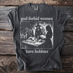 Dark gray t-shirt with the text "god forbid women have hobbies" and a graphic of witches.