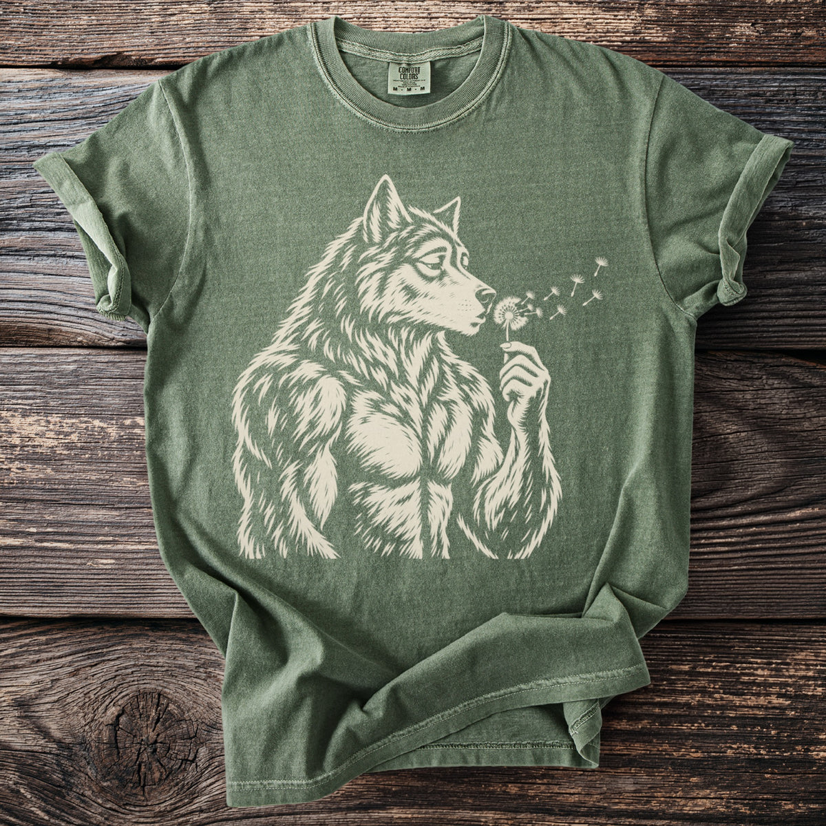 Green t-shirt with a cream graphic of a muscular wolf blowing on a dandelion.
