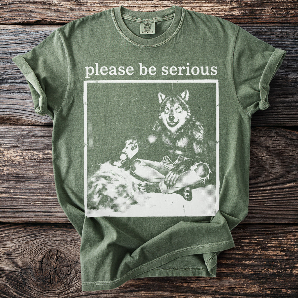 Green t-shirt with "please be serious" and a wolf in jeans graphic.