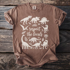 Brown t-shirt with white dinosaurs and "respect the locals" text graphic.