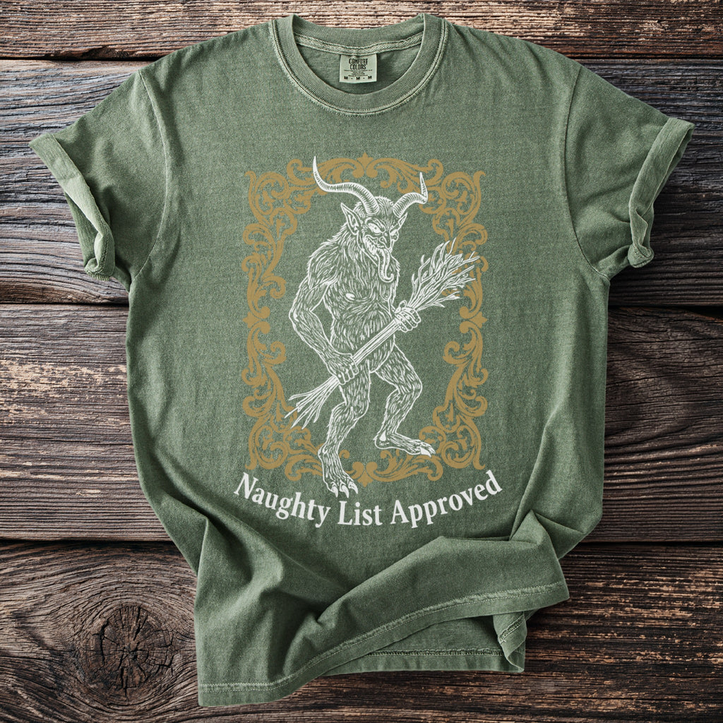 Green t-shirt with demon figure holding birch branches and text "Naughty List Approved."