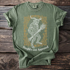 Green t-shirt with demon figure holding birch branches and text "Naughty List Approved."