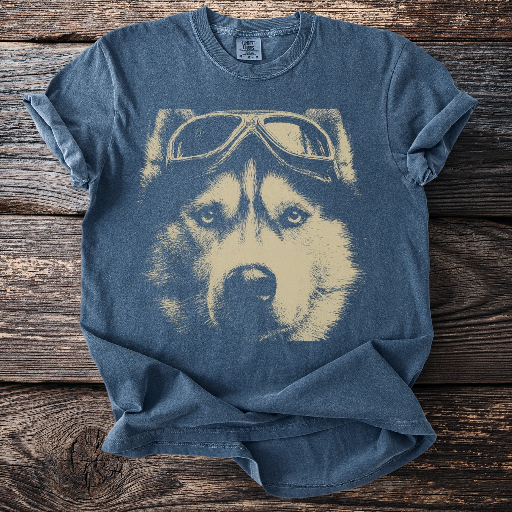 Blue t-shirt with a tan graphic of a husky wearing pilot goggles.