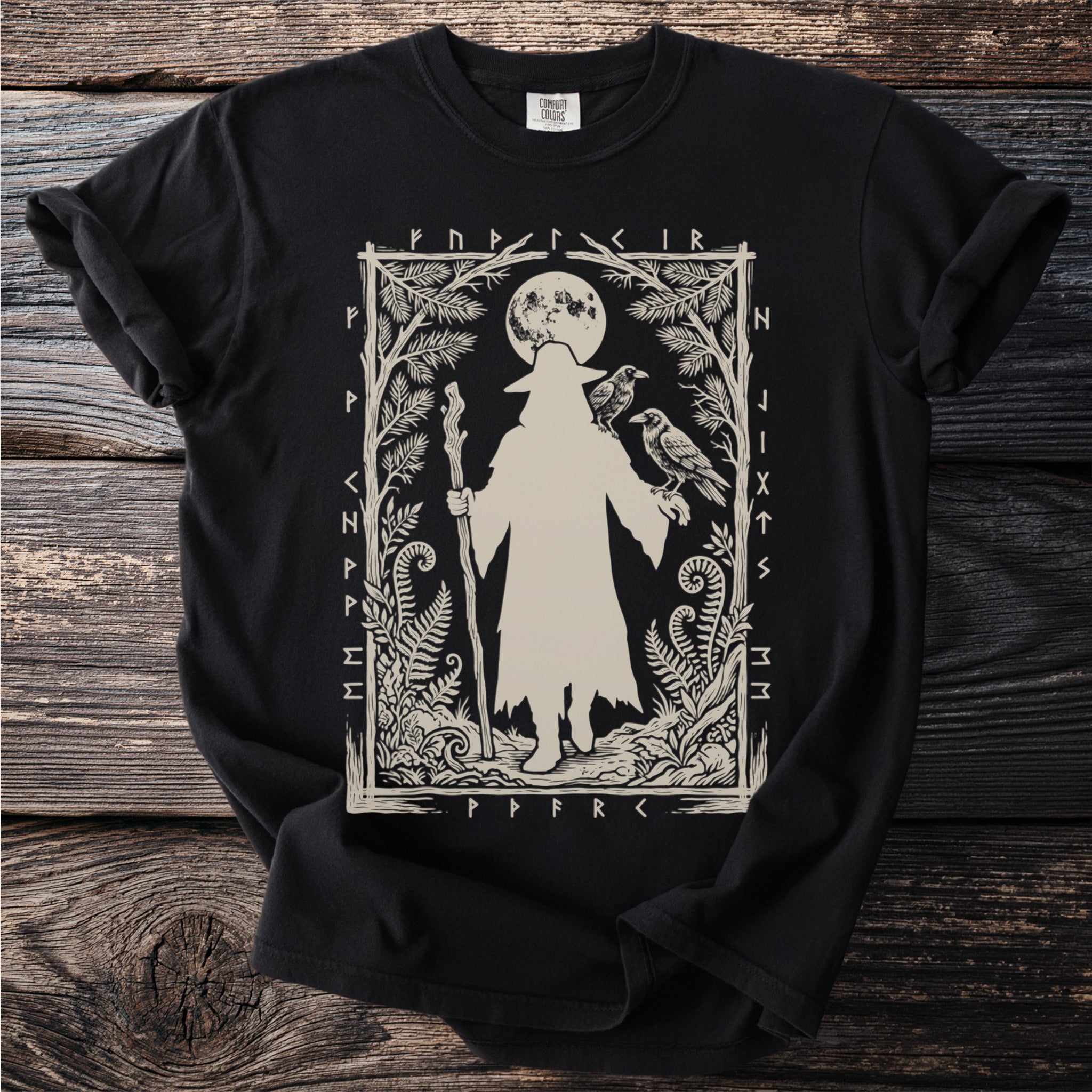 Black t-shirt with a beige graphic of a robed figure with a staff, two ravens, and moon.