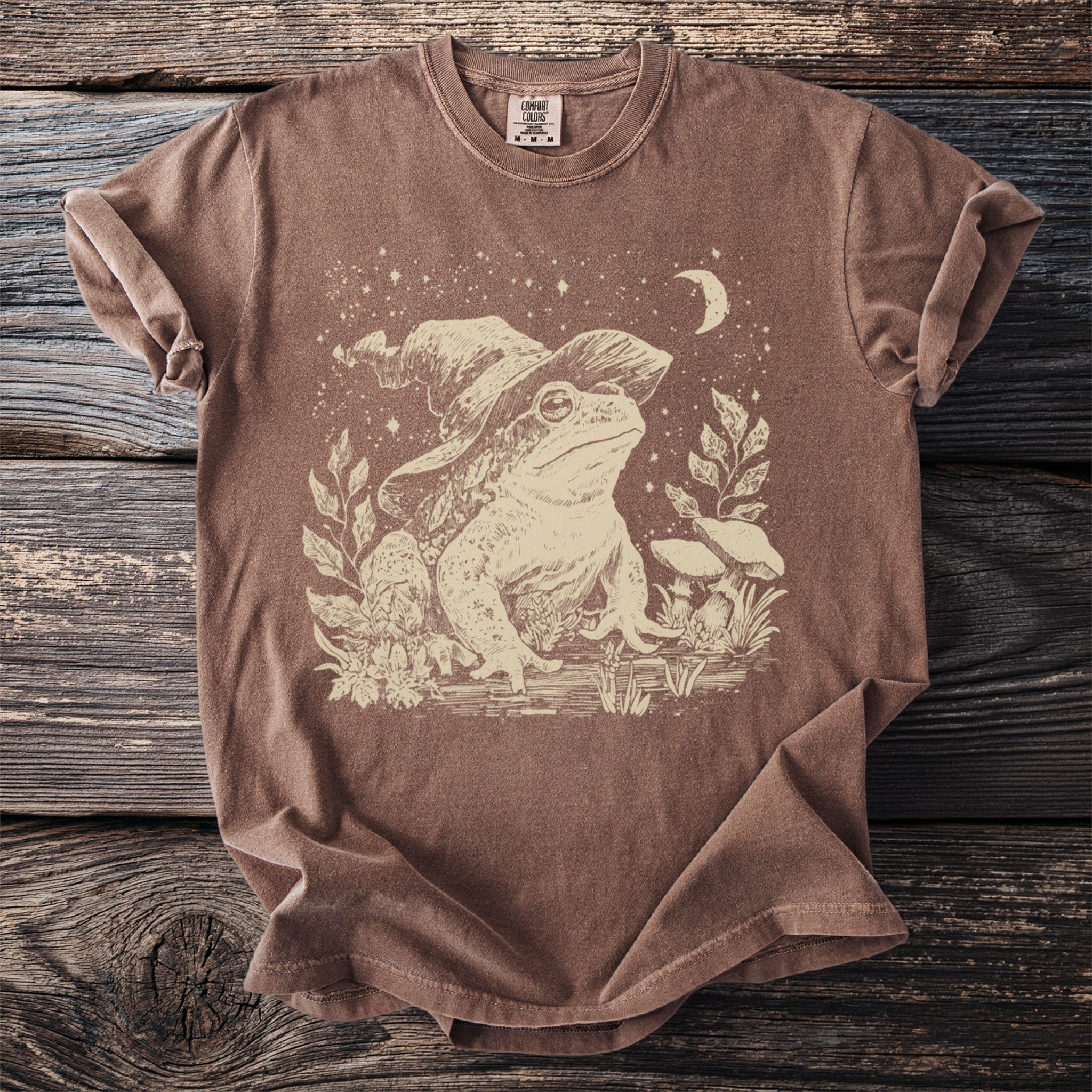 Brown t-shirt with a faded graphic of a frog wearing a wizard hat.