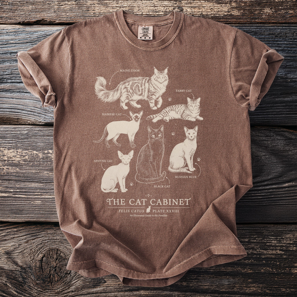 Brown t-shirt with white line art of six cat breeds titled "The Cat Cabinet"