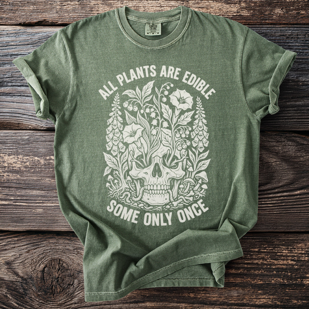 Green t-shirt with a white graphic of a skull surrounded by plants and the text "ALL PLANTS ARE EDIBLE SOME ONLY ONCE".