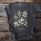 Gray t-shirt with "The Tea Garden" text and botanical illustrations of tea ingredients.