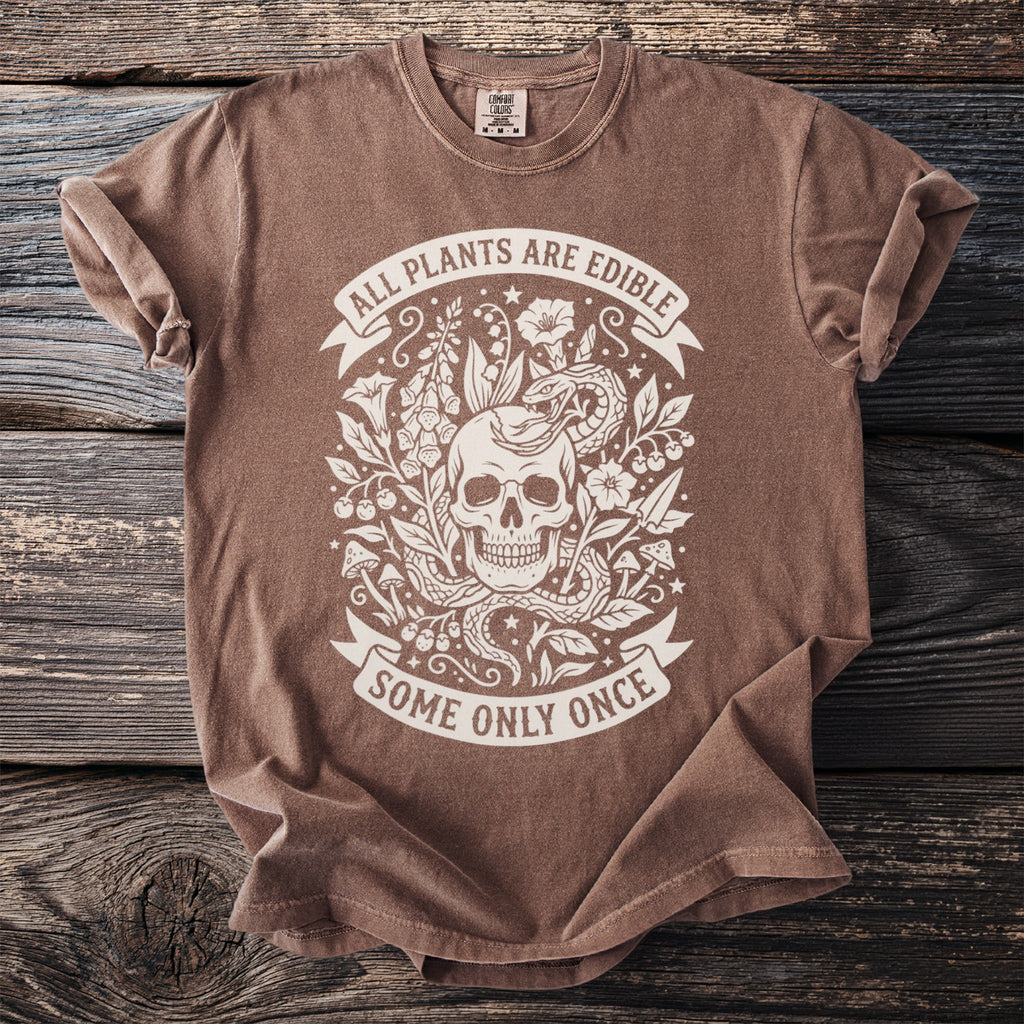 Brown t-shirt with skull, snake, and plants graphic and text "ALL PLANTS ARE EDIBLE SOME ONLY ONCE".