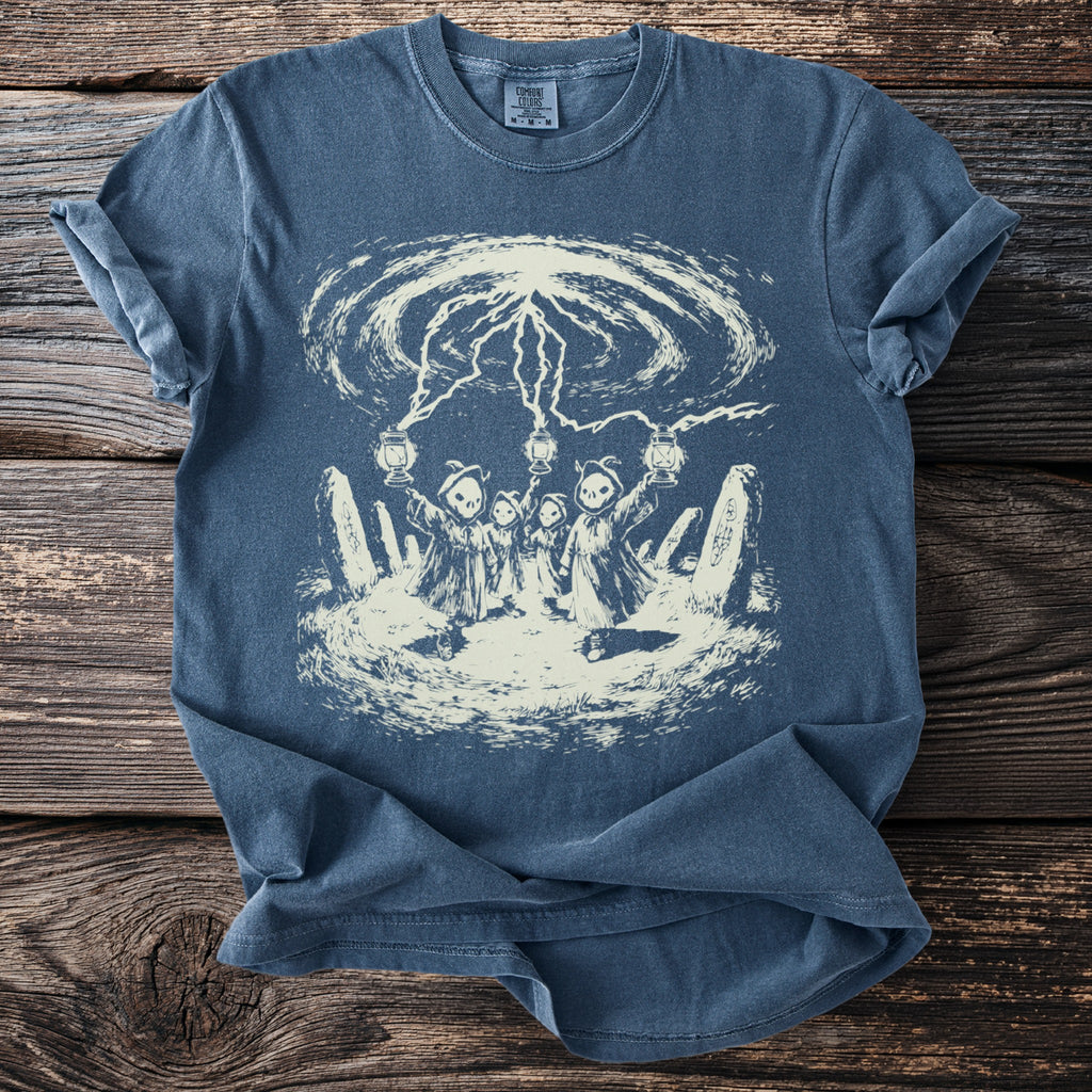 Blue t-shirt with a cream graphic of hooded figures holding lanterns under lightning bolts.