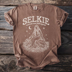 Brown t-shirt with white "SELKIE scottish seal folk legend" and mythical creature design.