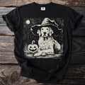 Golden retriever wearing a witch hat next to a carved pumpkin under a moon.