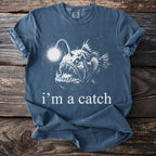 Blue t-shirt with a graphic of an anglerfish and text that reads "i'm a catch".