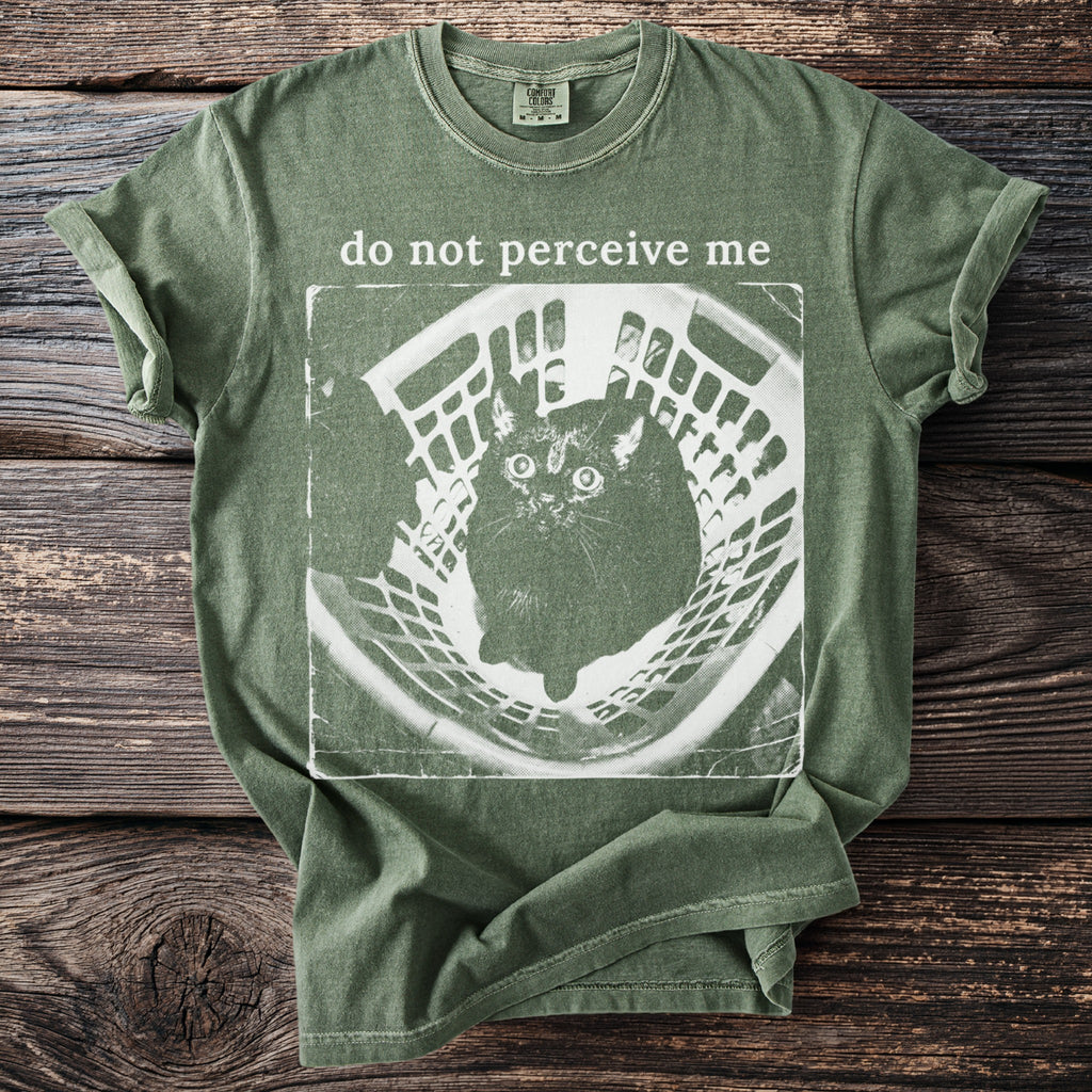 Green t-shirt with a distressed print of a startled cat in a basket and text "do not perceive me".