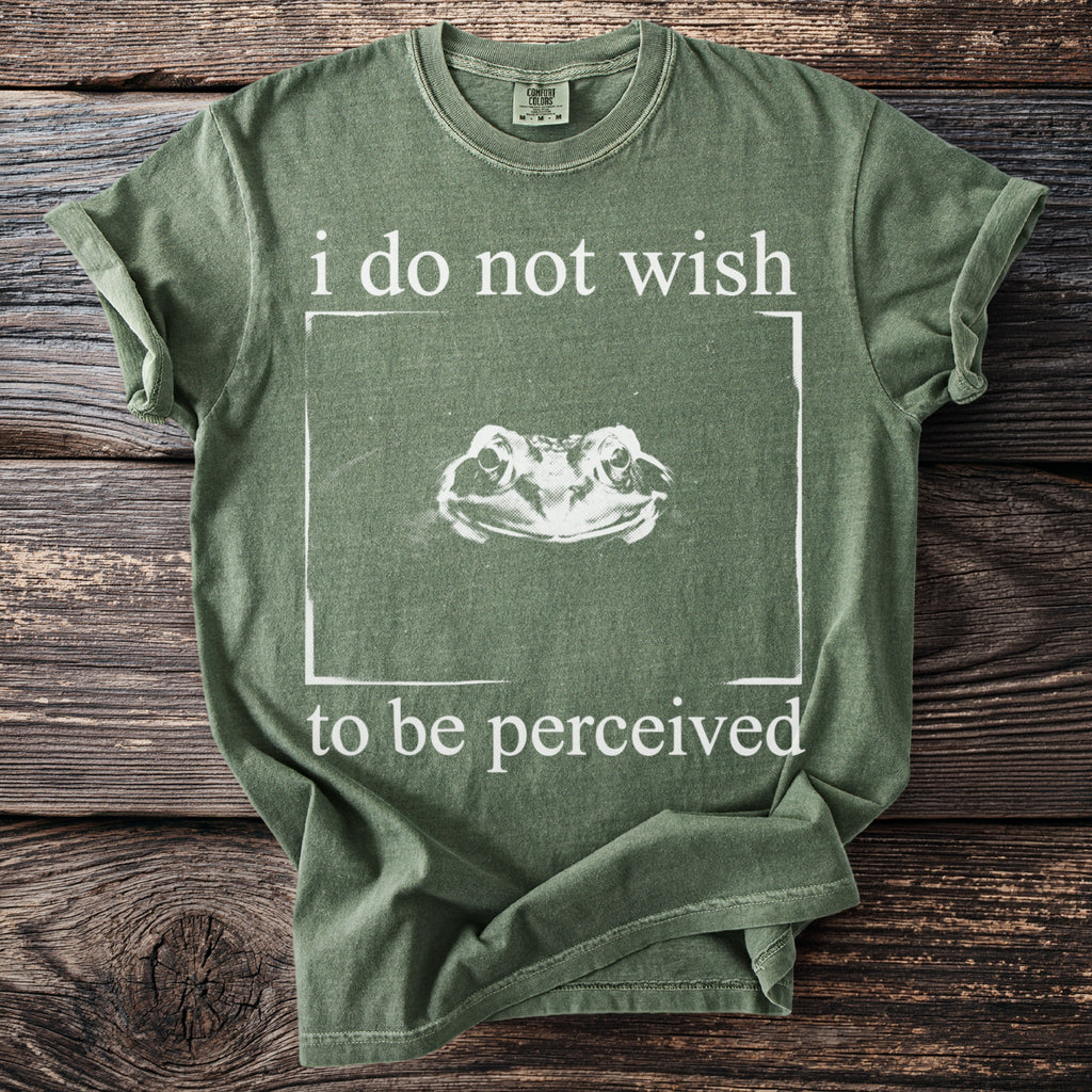 Green t-shirt with "i do not wish to be perceived" and a frog's head in a box.