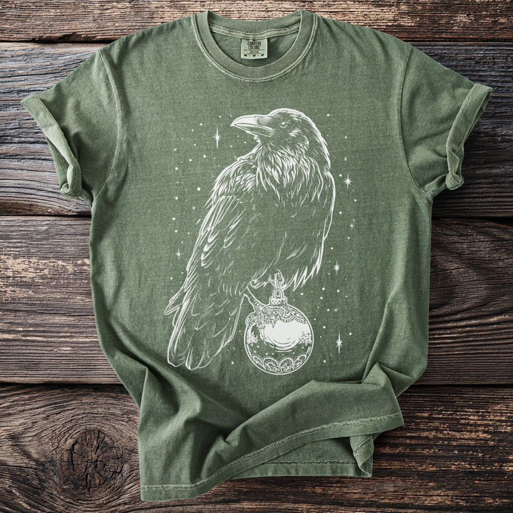 Green t-shirt with white line art of a raven perched on an ornate globe with stars.