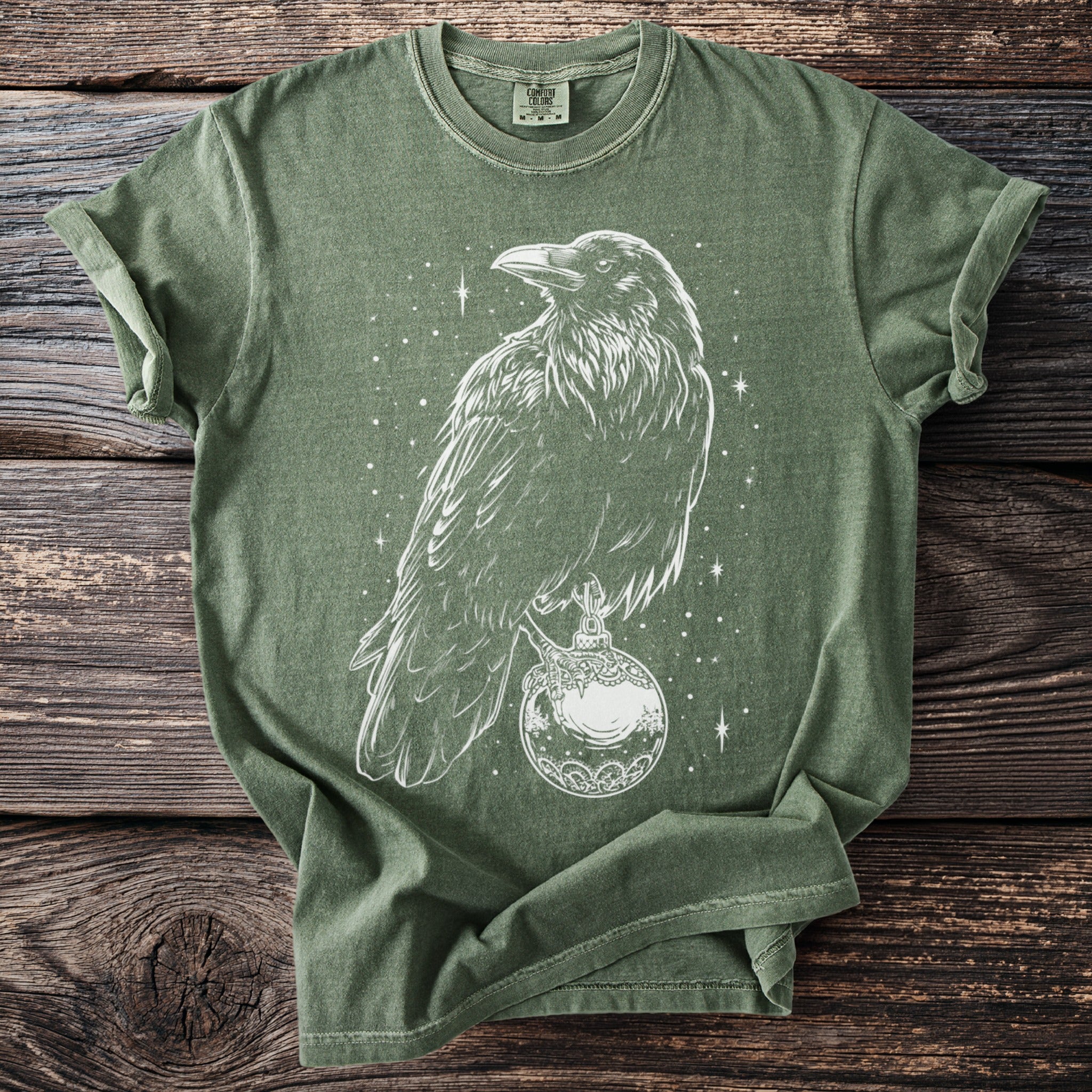 Green t-shirt with white line art of a raven perched on an ornate globe with stars.