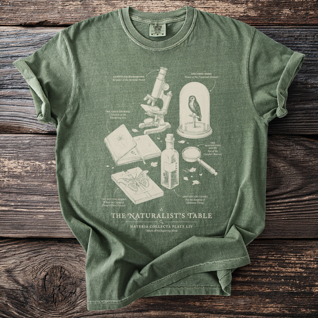 Green t-shirt with "The Naturalist's Table" graphic featuring a microscope, owl, and specimen board.