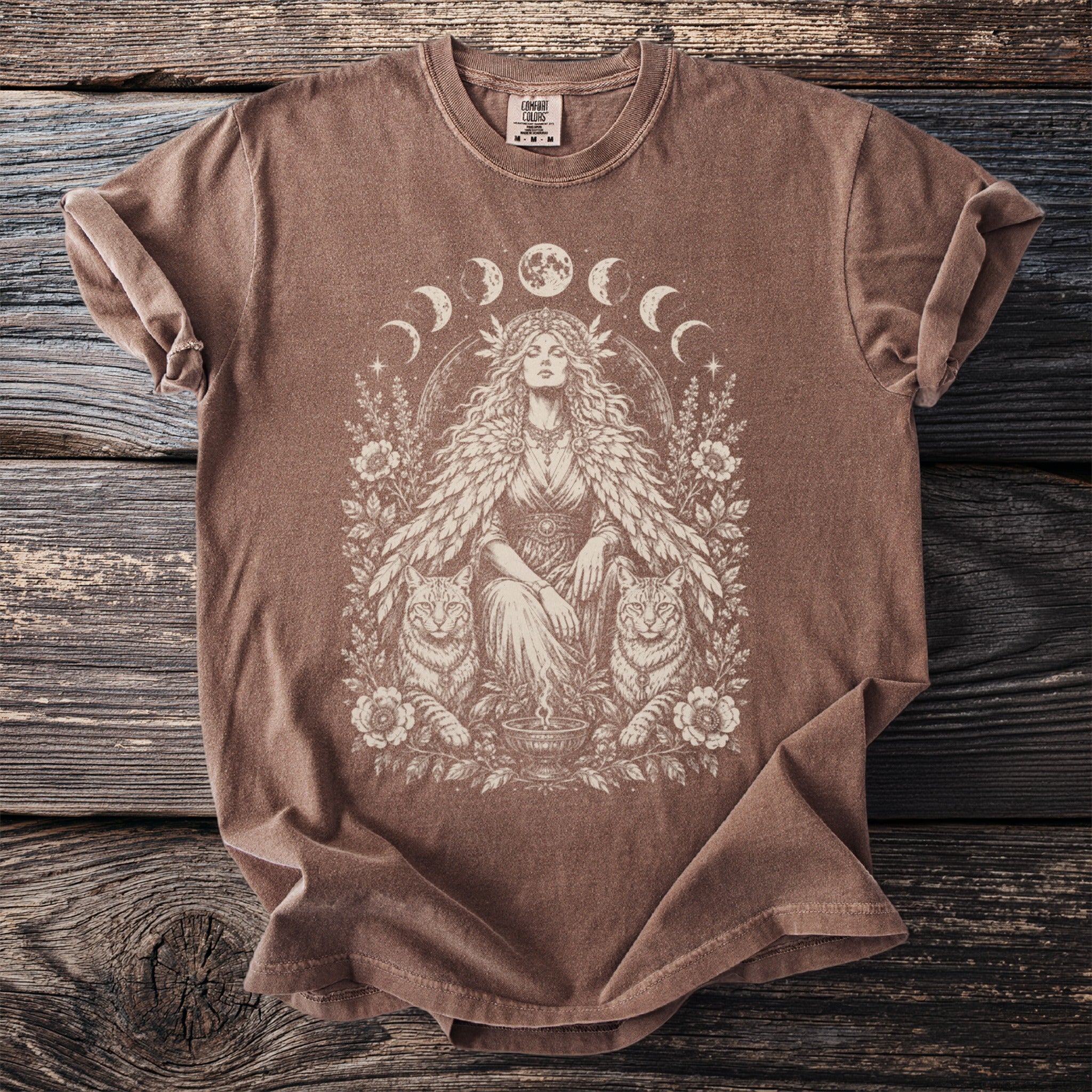Brown t-shirt with a vintage-style graphic of a woman and cats surrounded by moons and flowers.