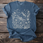 Blue t-shirt with a white line drawing of dragonflies, dandelions, flowers, moon, and stars.