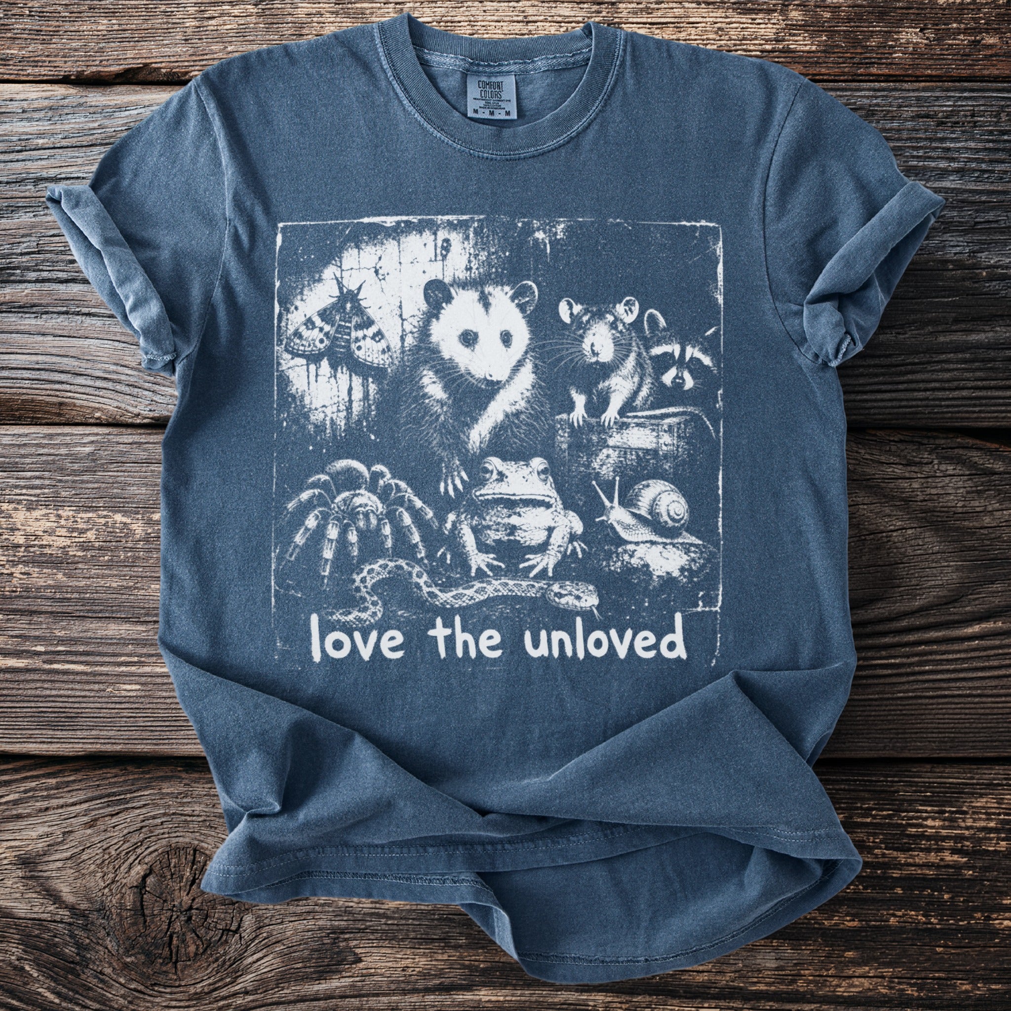 Blue t-shirt with graphic of moth, opossum, rat, raccoon, spider, frog, snail, and snake.