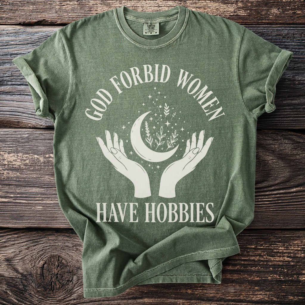 Green t-shirt with white text and graphics featuring 'God forbid women have hobbies'.