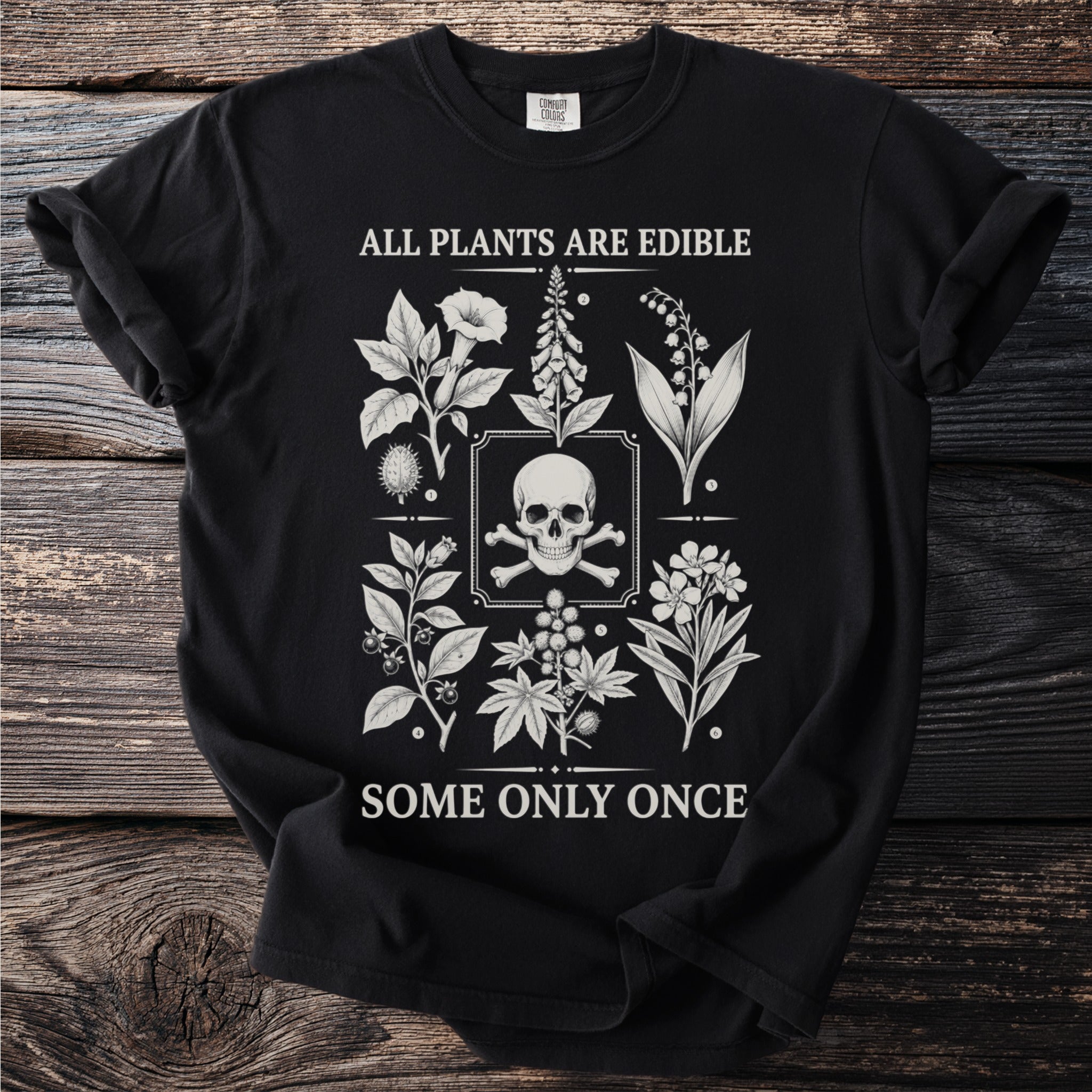 Black t-shirt with skull and crossbones, plants, and text "ALL PLANTS ARE EDIBLE SOME ONLY ONCE."