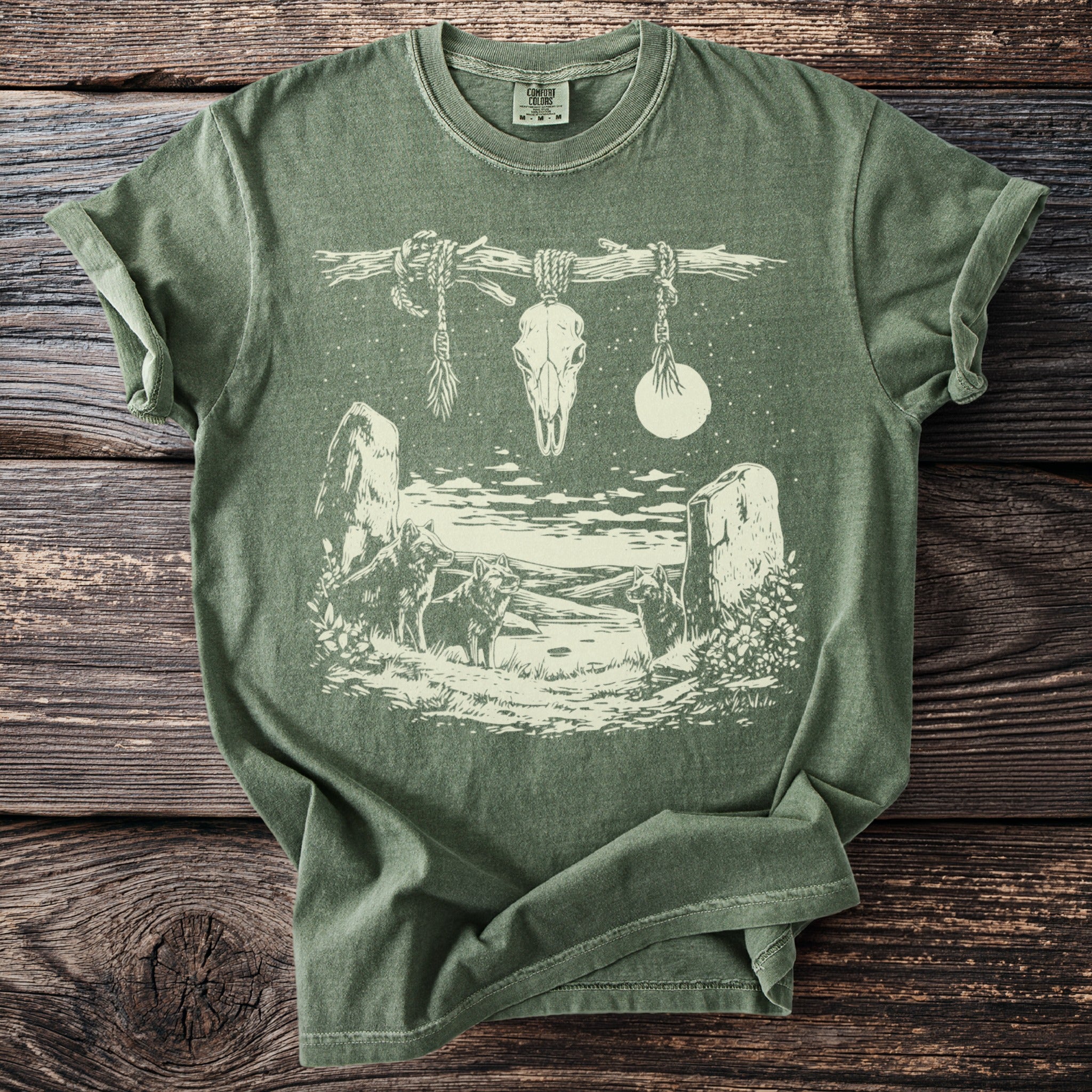Green t-shirt with graphic of wolves, skull, moon, and standing stones.