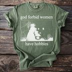 Green t-shirt with "god forbid women have hobbies" text and witchy image.