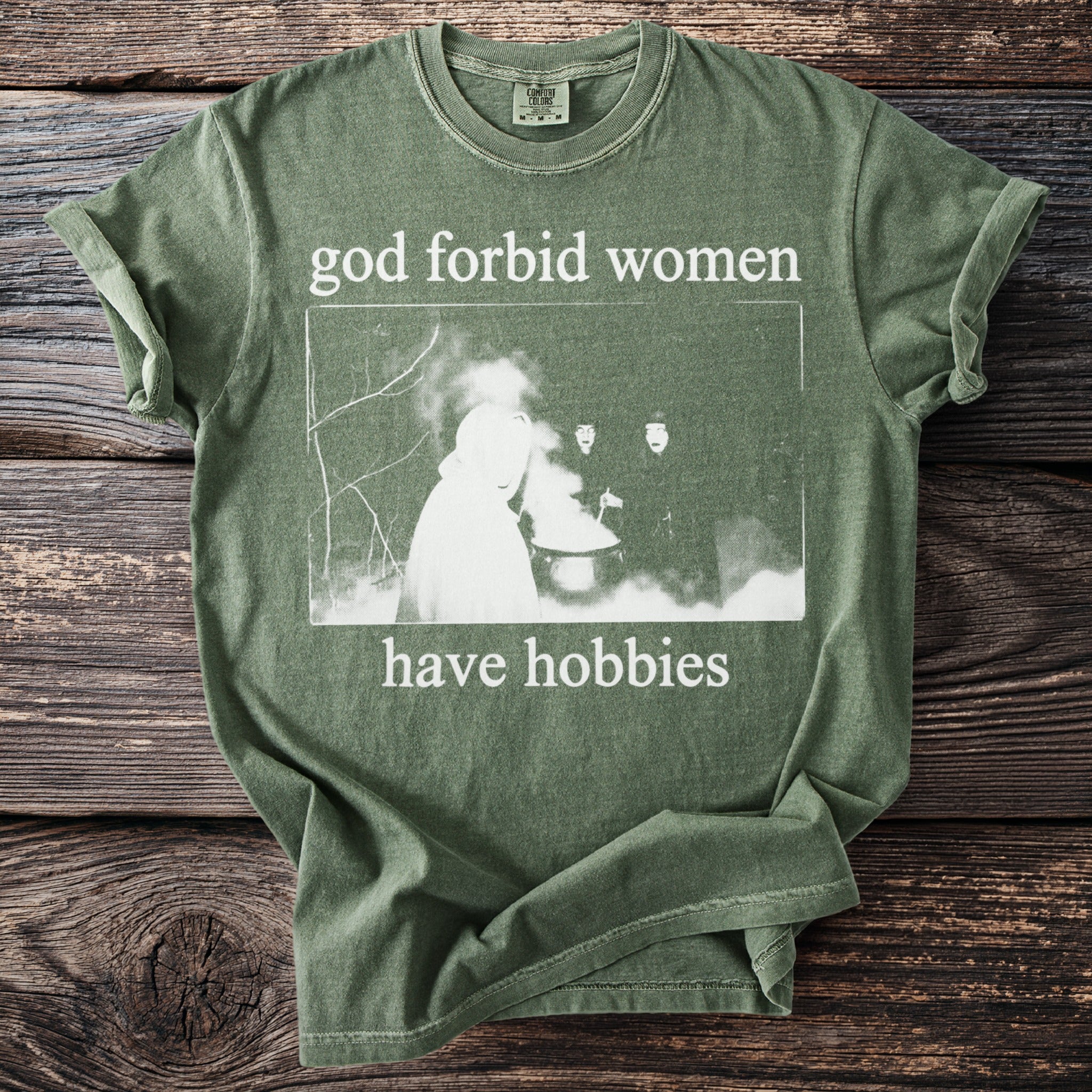 Green t-shirt with "god forbid women have hobbies" text and witchy image.