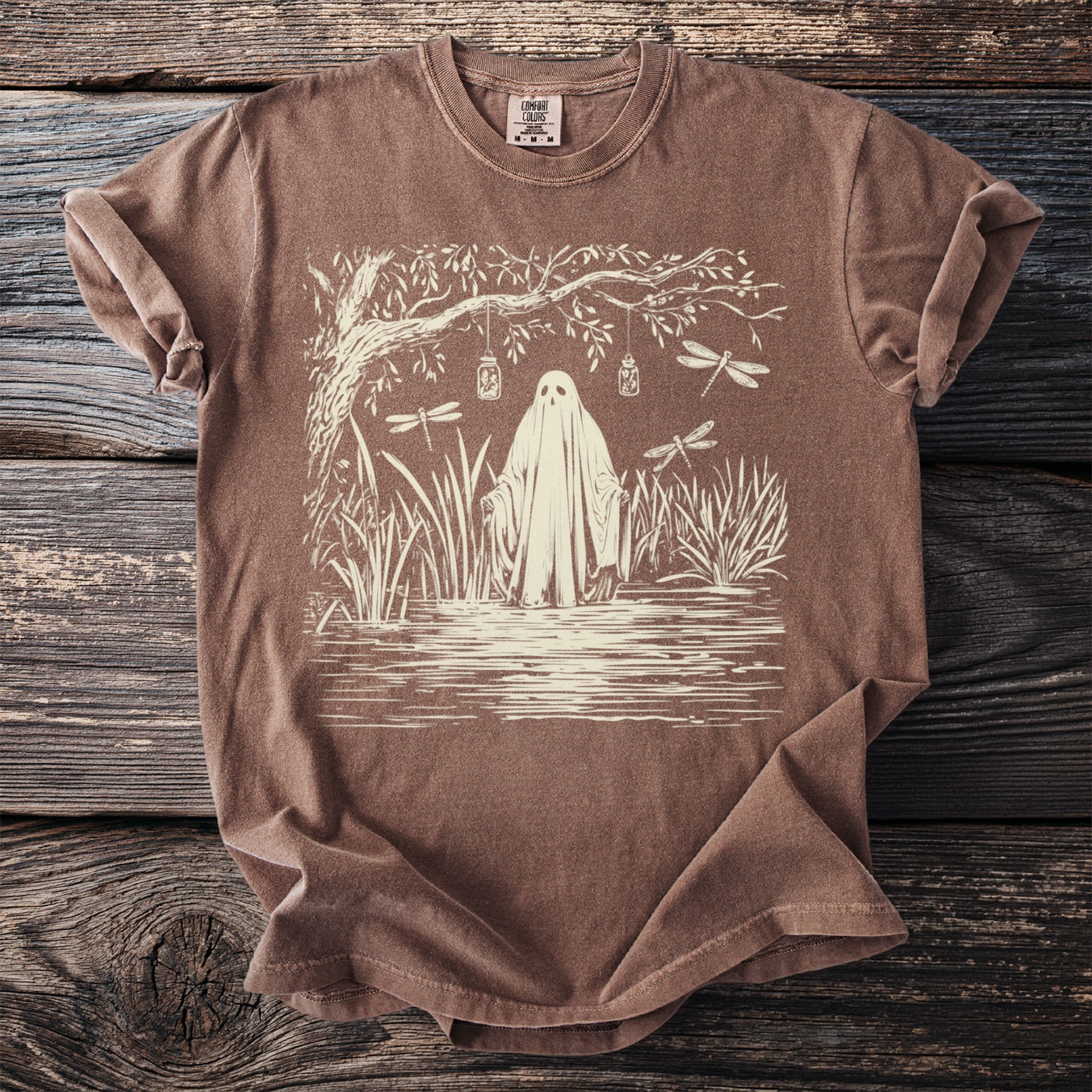 Brown t-shirt with ghost, dragonflies, and jars hanging from a tree.