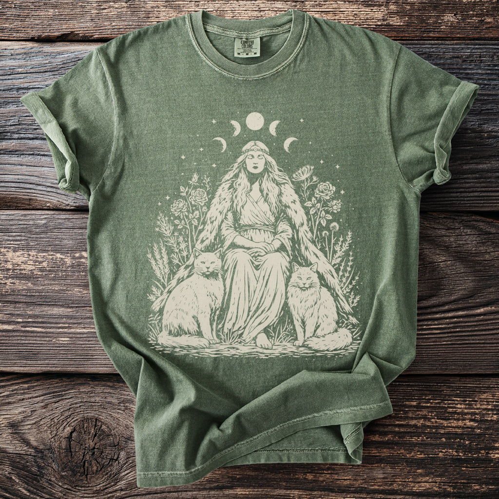 Green t-shirt with a woman, moon phases, flowers, and two cats in a line drawing.