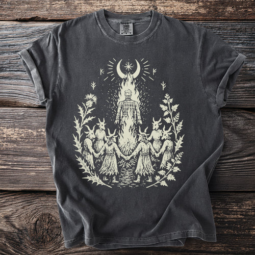 Dark gray t-shirt with a burning wicker figure encircled by participants in goat masks, with a crescent and star above.
